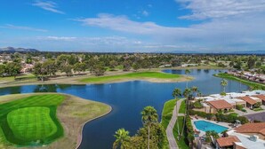 Un campo da golf con un lago, una piscina e edifici residenziali.
