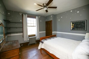 A bedroom with a wooden bed, a ceiling fan, a window with curtains, a radiator, and a wall with star decals. - Large, kid friendly, private home on a brick street, 10 mins from downtown (Pittsburgh)
