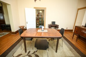 A dining room with a wooden table, four chairs, and a rug. There is a door leading to another room with shelves and a desk. - Large, kid friendly, private home on a brick street, 10 mins from downtown (Pittsburgh)