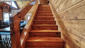 A wooden staircase with a handrail leading to an upper floor.