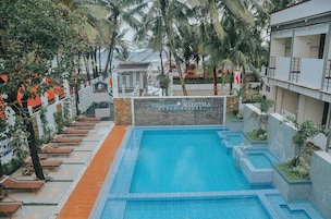 Una piscina con sillas de descanso y palmeras, rodeada por un edificio con un letrero que dice "Villa Maristela Beach Resort".