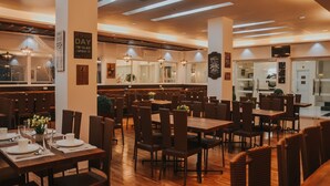 Un restaurant spacieux avec de hauts plafonds, un éclairage moderne et des tables et des chaises disposées avec soin.