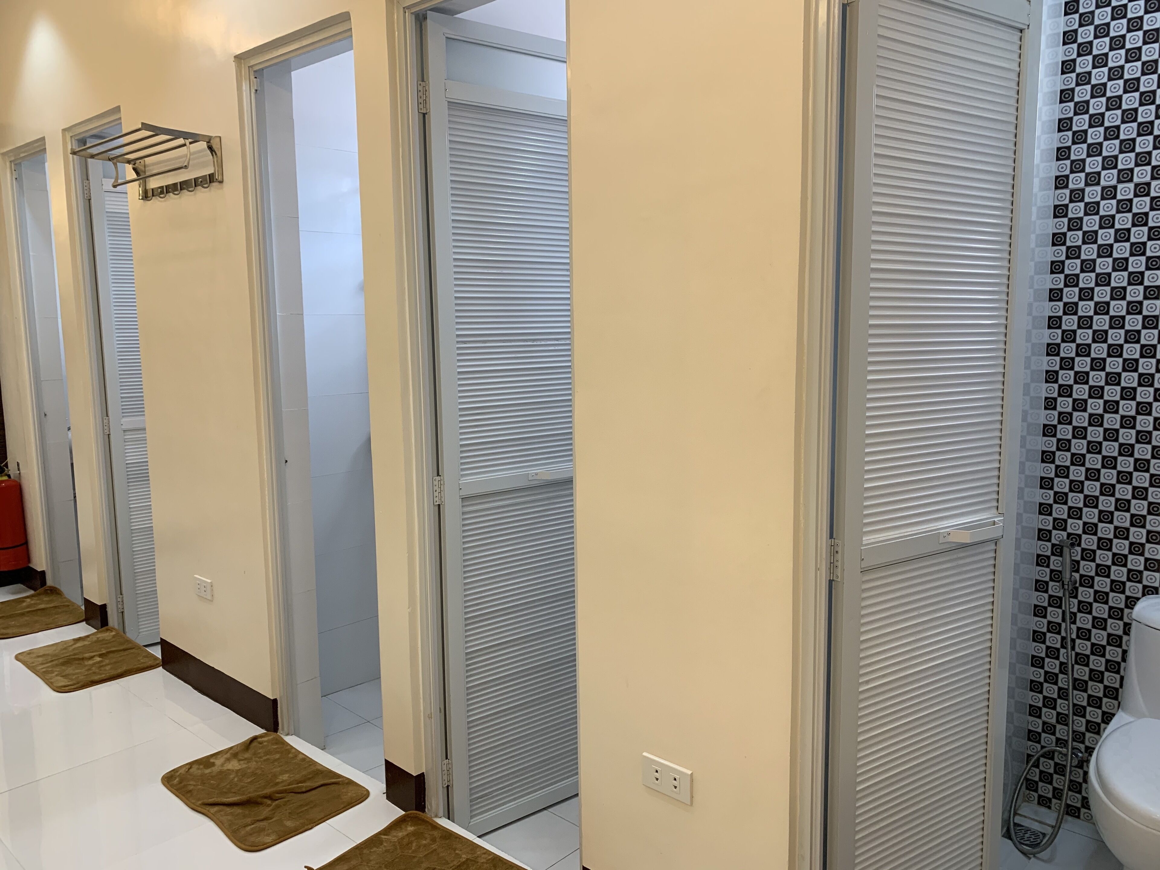 Un pasillo con puertas cerradas, un perchero y un papel tapiz decorado cerca del inodoro.