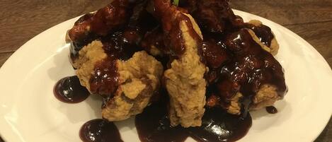 A plate of fried chicken with gravy and a green garnish on a white plate.