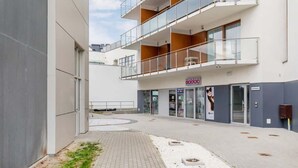 Un edificio moderno con fachada de vidrio, entrada visible y un letrero que indica un sanitario.