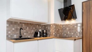 Una cocina moderna con armarios blancos, un salpicadero estampado, un grifo negro y una cafetera.