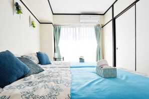 Een slaapkamer met een bed, een nachtkastje, een raam met gordijnen en een airconditioning.