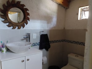 Bathroom features a white sink, mirror, and toilet with a simple tiled backsplash.