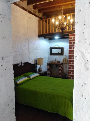 Cozy retreat with a traditional bed, wooden headboard, and brick fireplace.