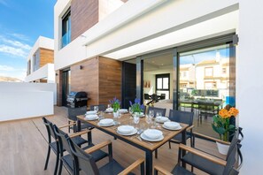 A dining area with a table set for six, outdoor seating, and a barbecue grill. - Fidalsa 5 Stars Premium (El Campello)