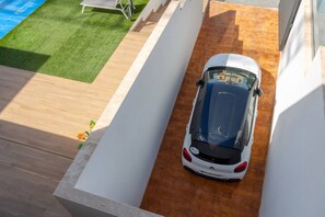 A white car parked in a narrow driveway with a wooden floor and a white wall on one side. - Fidalsa 5 Stars Premium (El Campello)