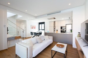 Un salon moderne avec un canapé blanc, un coin repas et une cuisine.