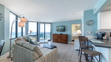 A spacious living area with a sofa, a dining table, and a kitchen area with a bar.