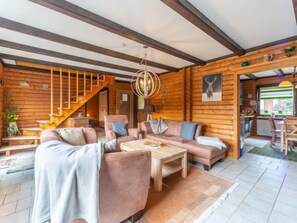 Ein gemütliches Blockhaus-Interieur mit Wohnbereich, einer Treppe und einem Essbereich.