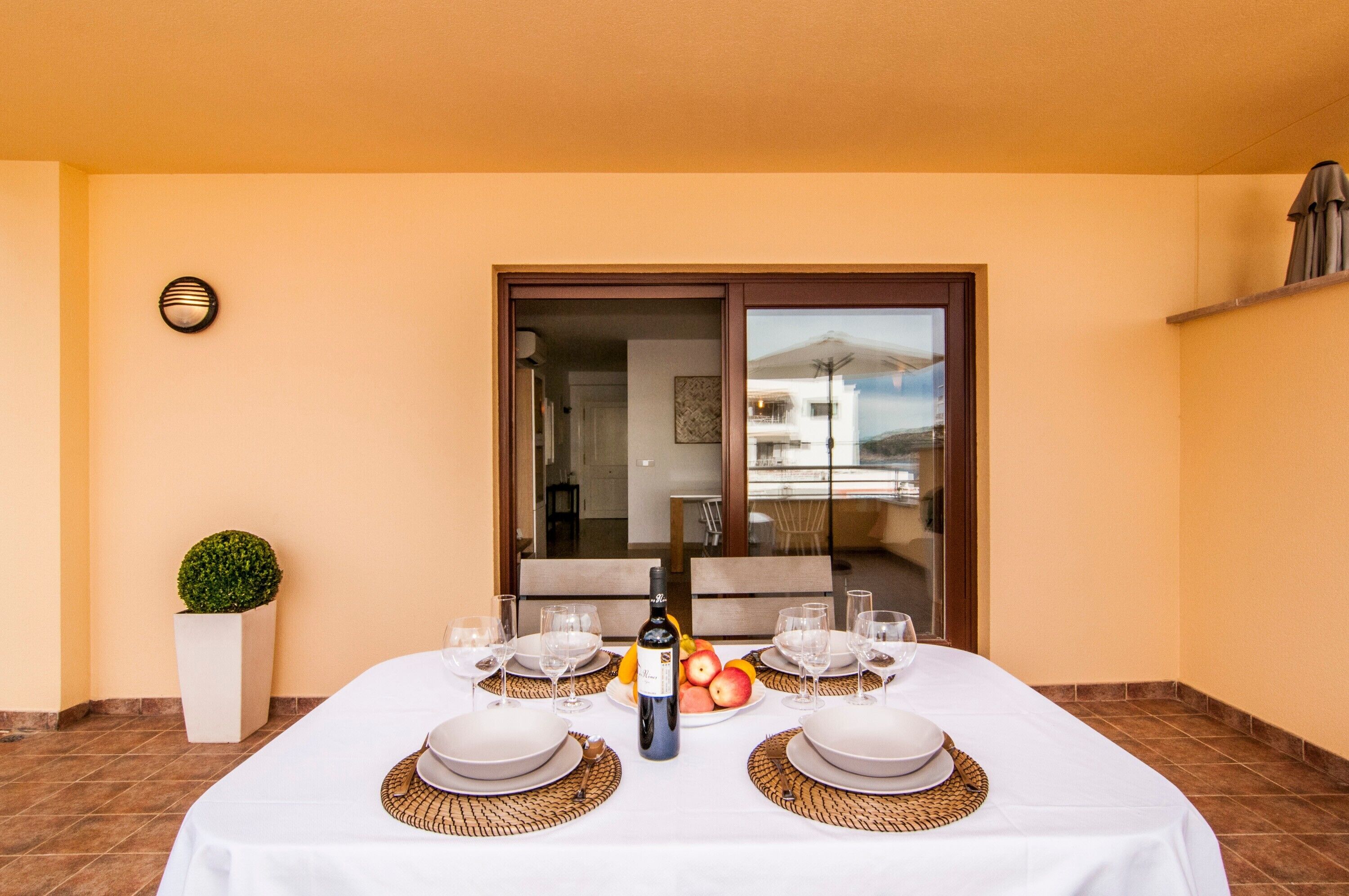 A dining table set with plates, glasses, a bottle, and fruit.