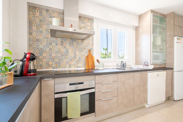 Una cocina moderna con un salpicadero con diseño, horno empotrado y lavavajillas.