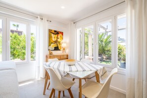 Een eetruimte met een tafel, stoelen en een schilderij aan de muur.