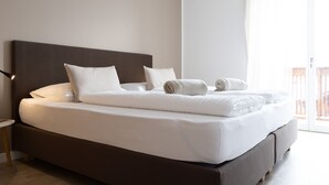 A modern hotel room with a large bed, a nightstand, and a view of the outside. - Lovingly Furnished Apartment with Balcony and Stunning City Views in the Residence (Marling)