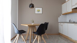 A modern kitchen with a dining table, two chairs, a hanging light fixture, and a framed picture on the wall. - Lovingly Furnished Apartment with Balcony and Stunning City Views in the Residence (Marling)
