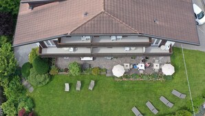 Kaksikerroksinen rakennus, jossa on patioalue, jossa on ulkotilaa istumiseen ja nurmikko.