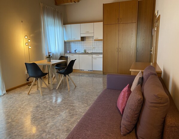 Un espace de vie compact comprenant un coin repas, une kitchenette et un canapé.