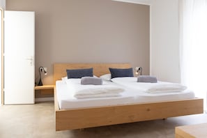 Une chambre à coucher moderne avec un lit en bois, deux oreillers, une table de chevet et une commode.