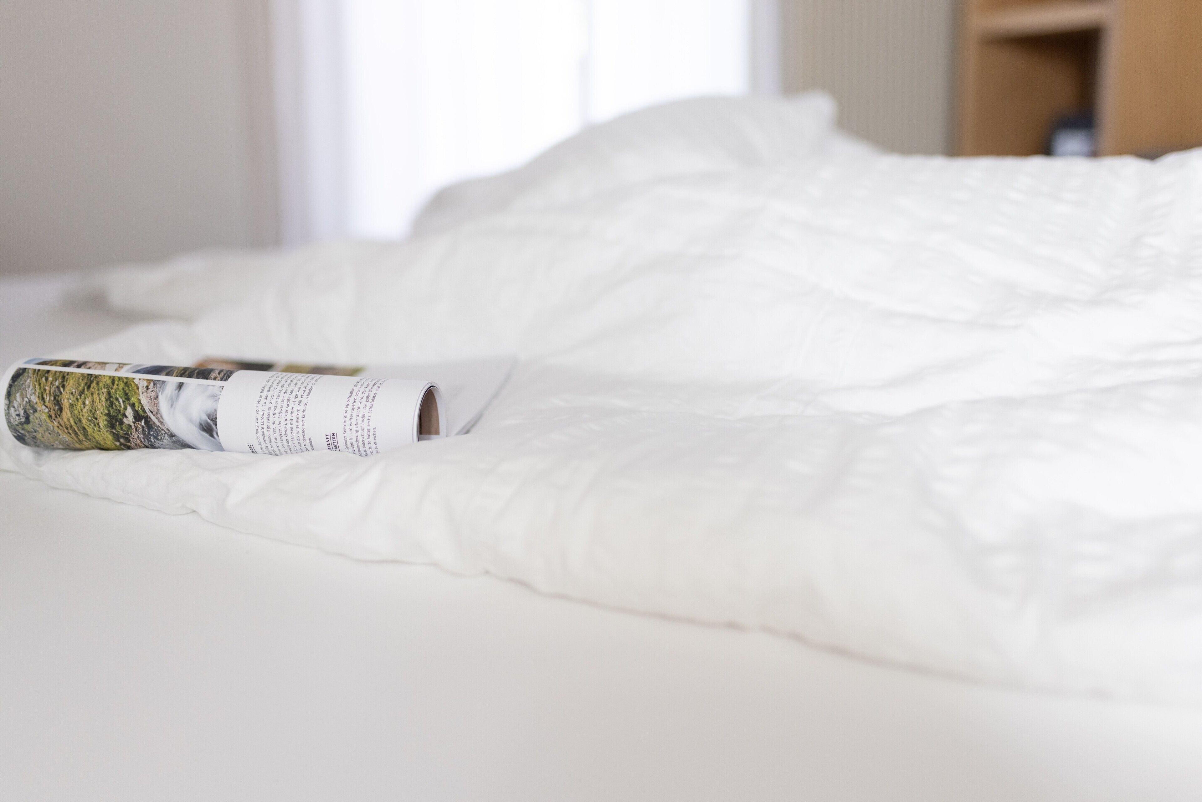 A bed with a magazine on it.