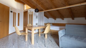 Una habitación con techo de madera, una mesa de comedor con sillas, un sofá y una cama.
