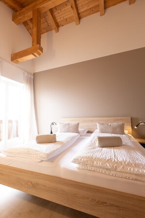 Un grand lit avec une tête de lit en bois, du linge de lit blanc et une table de chevet avec une lampe.