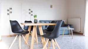 A modern dining area with a wooden table, black chairs, and a blue sofa. - Lovingly Furnished Apartment with Balcony and Stunning City Views in the Residence (Marling)