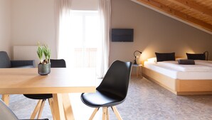 A room with a wooden ceiling, a bed, a table with a chair, a potted plant, and a television. - Lovingly Furnished Apartment with Balcony and Stunning City Views in the Residence (Marling)