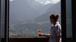 A person holding a glass, with a mountainous landscape visible through a window. - Lovingly Furnished Apartment with Balcony and Stunning City Views in the Residence (Marling)