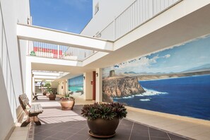 A hotel lobby with a mural of a coastal scene, a wooden bench, and potted plants. - Maritime Holiday Home Casa Yerida with Pool and Wi-Fi (Cotillo)