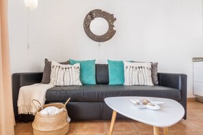 A living room with a black sofa, teal and white pillows, a white coffee table, and a woven basket. - Maritime Holiday Home Casa Yerida with Pool and Wi-Fi (Cotillo)