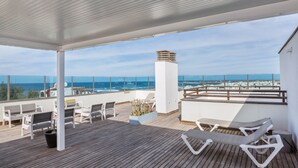 A wooden deck with lounge chairs, a table, and a view of the ocean. - Maritime Holiday Home Casa Yerida with Pool and Wi-Fi (Cotillo)