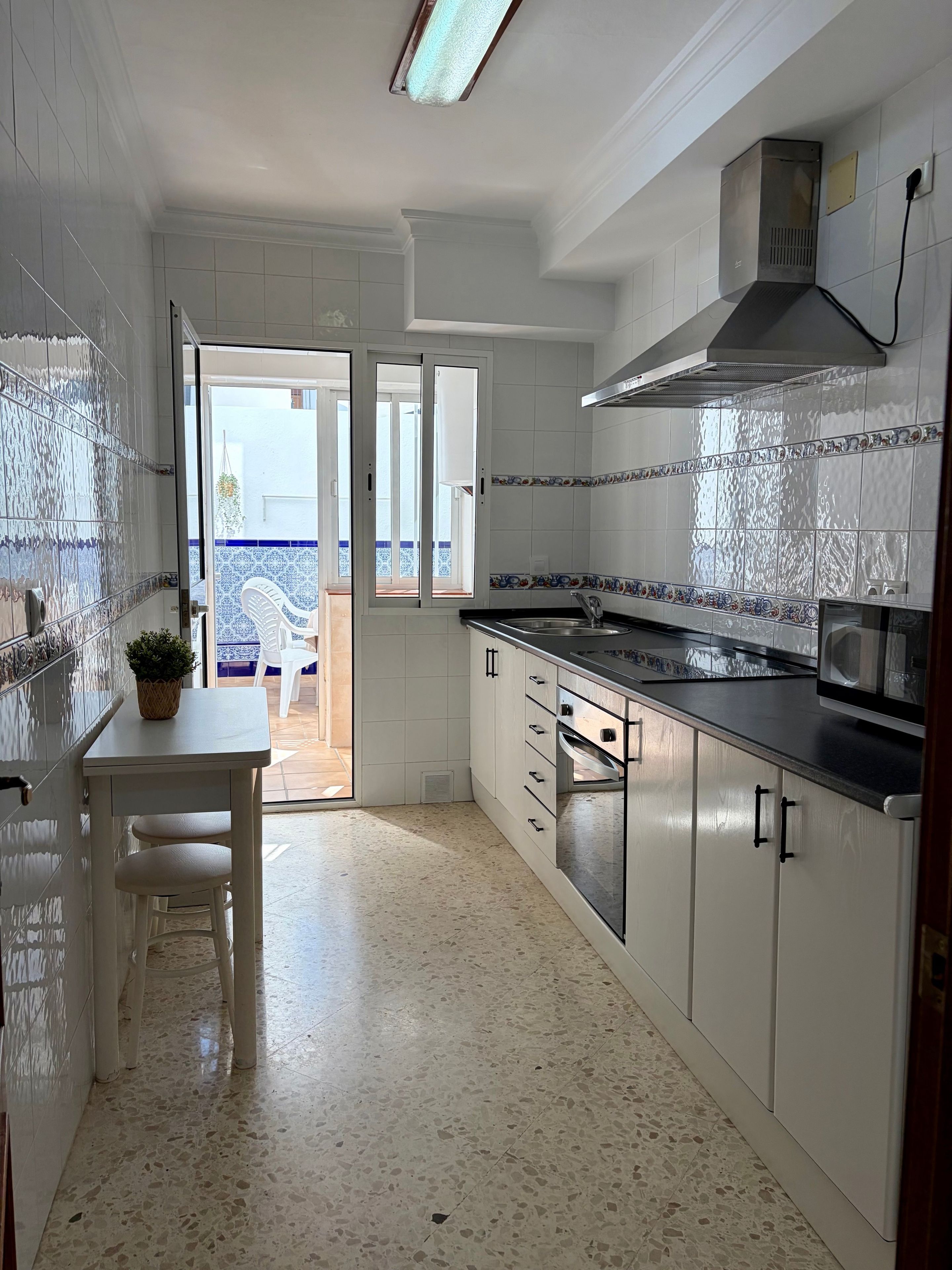 Una cocina con armarios blancos, una encimera y un microondas.