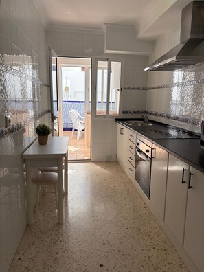 Une cuisine avec des meubles blancs, un plan de travail et une vue sur l’extérieur.