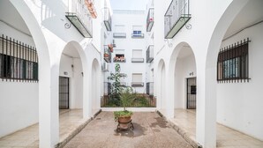 A courtyard with white walls, arched doorways, and a central potted plant. - Newly Renovated Apartment “Conil Centro” with Wi-Fi, Terrace & Air Conditioning; Parking Available (Conil de la Frontera)