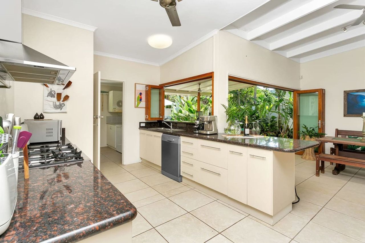 A kitchen with a central island, a dishwasher, and a stove. There is a dining area with a table and chairs.