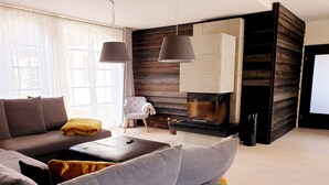 A modern living room with a sofa, ottoman, and a fireplace. - Vacation home for 20 people, fireplace, sauna, 10 rooms, 10 bathrooms, very large, distant view (Altenberg)
