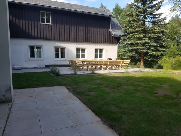A house with a dark exterior, white trim, and a patio area with a wooden table and chairs.