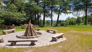 A circular outdoor seating area with benches and a central fire pit, surrounded by a stone-paved circle. - Vacation home for 20 people, fireplace, sauna, 10 rooms, 10 bathrooms, very large, distant view (Altenberg)
