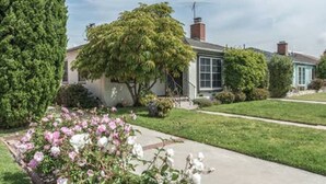 A residential house with a well-maintained lawn, a flower bed with pink flowers, and a clear sky. - Silicon Beach Escape (Los Angeles)