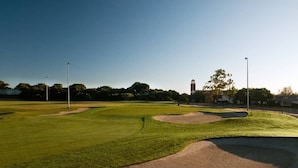 A golf course with sand bunkers, a clear sky, and a distant building with a tower. - Silicon Beach Escape (Los Angeles)