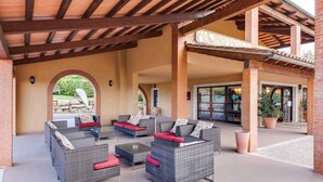 Ein Terrassenbereich im Freien mit Korbmöbeln und einem steinernen Bogen.