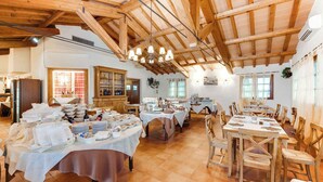 Ein geräumiger Speisesaal mit hohen Holzbalkendecken und mehreren gedeckten Tischen.