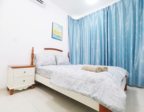 Ein Schlafzimmer mit einem Bett, einem Nachttisch, einer Wand-Klimaanlage, einem Gemälde und blauen Vorhängen.