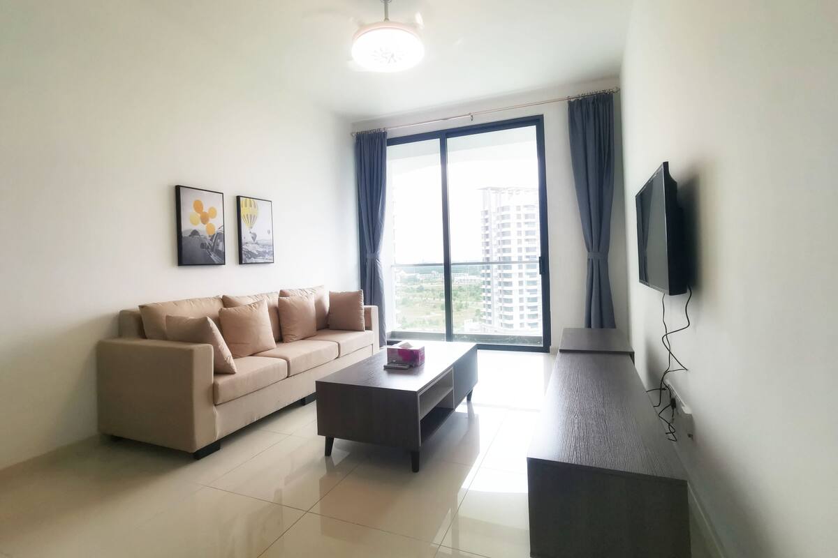 A modern living room with a sofa, coffee table, and a flat-screen TV mounted on the wall.