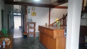 A reception area with a wooden desk, a clock on the wall, and a staircase leading upstairs. - Diamond Star Guest House (Nyaungshwe)