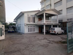 A two-story building with a balcony, a parked van, and a bus in the foreground. - Diamond Star Guest House (Nyaungshwe)